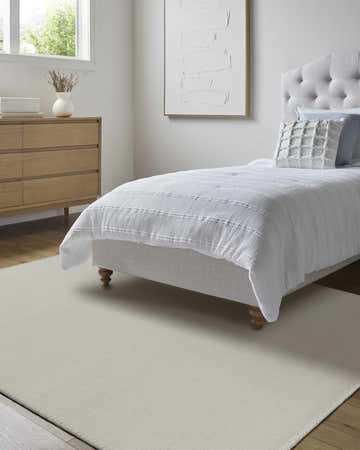 Light, airy bedroom with wood floors and the ivory Ayumu Area Rug under a gray upholstered bed. Roomscene-Rectangle