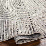 Close-up of the Brita Area Rug showing a bone and cloud gray geometric pattern and textured, machine-woven construction. Fold