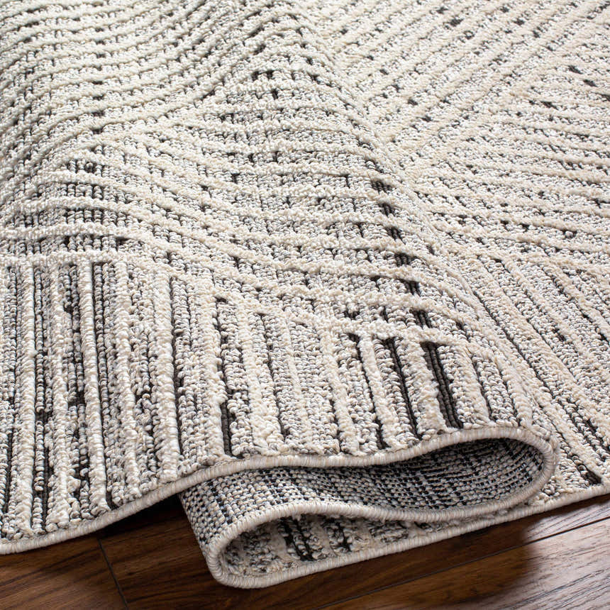 Close-up of the Brita Area Rug showing a bone and cloud gray geometric pattern and textured, machine-woven construction. Fold