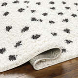Close-up of the Chaia Dotted Black & White Plush Rug, showing its soft shag texture and dotted animal print design. Fold