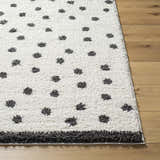 Close-up of Chaia Dotted Black & White Plush Rug. Soft, shag texture with black dots on a white background. Modern style. Front