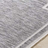 Close-up of Arnola Gray Outdoor Rug showing charcoal, cream, and gray woven texture and farmhouse style. Texture