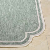Close-up of the Arnola Green Outdoor Rug, showing its cream and green woven texture and unique border design. Front