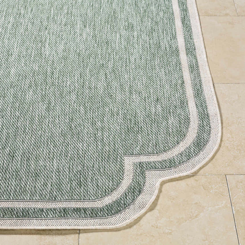 Close-up of the Arnola Green Outdoor Rug, showing its cream and green woven texture and unique border design. Front