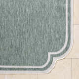 Close-up of the Arnola Green Outdoor Rug showing the texture and cream border detail. Corner