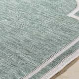 Close-up of the Arnola Green Outdoor Rug showing cream and green woven texture and runner edge detail. Texture