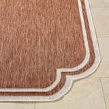 Close-up of Arnola Brown Outdoor Rug showing woven texture, burnt orange color, and cream border on tile floor. Front