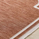 Close-up of the Arnola Brown Outdoor Rug, showing its woven texture and cream border detail. Texture