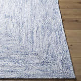 Close up of Kenyi Navy Area Rug showing hand woven texture and navy and white color on wood floor. Front