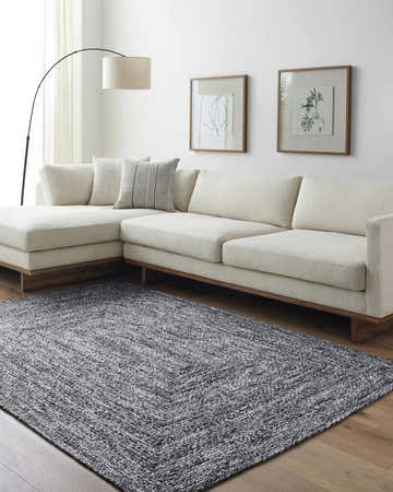 Living room scene with a Kenyi Black Area Rug, cream sectional sofa, wood floors, and minimalist art. Roomscene-Rectangle