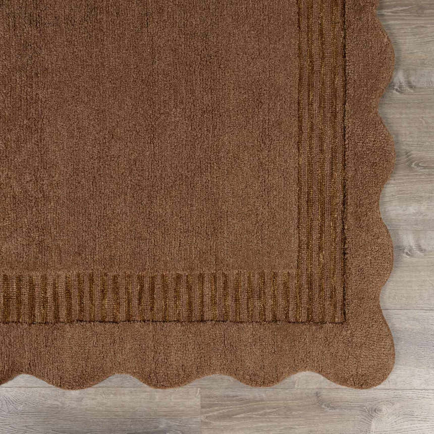 Close-up of the hand-tufted Gurib Border Wool Area Rug. Features a wavy edge and striped border in neutral brown tones. Corner