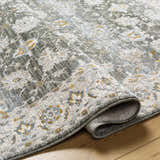 Close-up of the Amaru Green Textured Rug showing its floral pattern, texture, and colors like sage, gray, and mustard. Fold