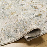 Close-up of the Emile Textured Rug with Fringes showing its off-white, gray, and mustard traditional pattern and textured weave. Fold