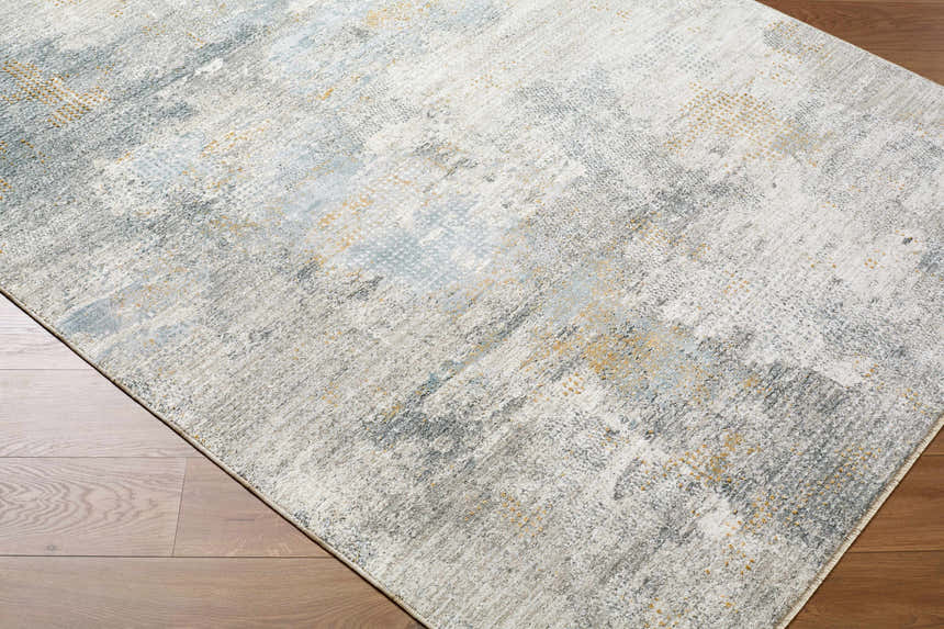 Close-up of the Gryta Textured Rug with Fringes. Features gray, light blue, and gold tones on a textured, contemporary design. Corner