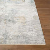 Close-up of the Gryta Textured Rug. Features a gray, light gray, and nutmeg abstract pattern on a soft polyester weave. Front
