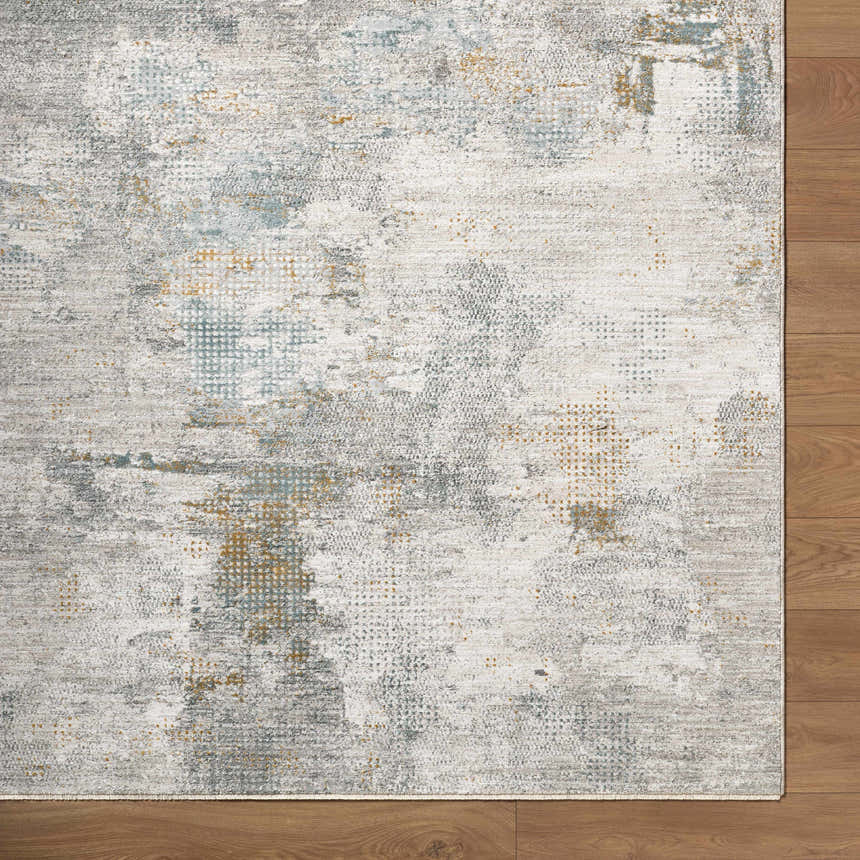 Close-up of the Gryta Textured Rug with Fringes. Features a gray, white, blue, and gold abstract pattern. Contemporary style. Corner