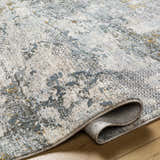 Close-up of the Pizi Textured Rug in light gray, ink blue, and mustard. Contemporary design with subtle texture. Fold