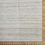 Close-up of the hand woven Anaya Cream Area Rug showing beige, bone, and gray tones, plus a fringe detail. Corner
