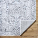 Close-up of Nadia Silver Gray Area Rug showing traditional pattern, light purple, silver gray, and non-slip backing. Fold