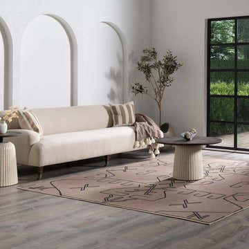 Living room with a camel Hamid Washable Jutely Rug, beige sofa, round coffee table, and arched wall decor. Roomscene-Rectangle