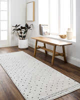 Entryway with a Julie Area Rug runner in beige and black, wood bench, and indoor plant. Roomscene-Runner