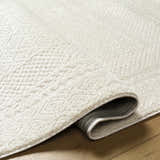 Close-up of the ivory Julio Area Rug showing its plush texture and subtle geometric pattern on hardwood floor. Fold