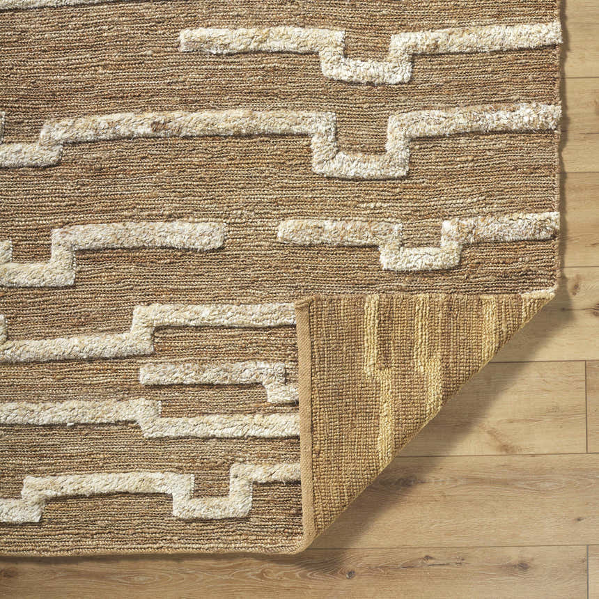 Close-up of the hand woven Miya Area Rug showing the jute texture and beige geometric pattern. Fold