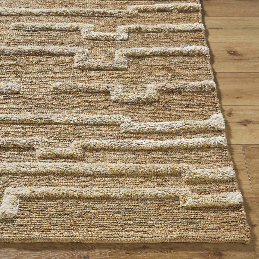 Close-up of the hand woven Miya Area Rug. Jute rug with beige geometric pattern and natural texture on wood floor. Front