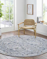 Light and airy room with round Irida Area Rug in dark gray, denim, and gray under a modern chair. Roomscene-Round