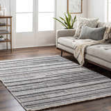 Living room scene with a gray sofa and the striped gray Silanga Area Rug on dark wood floors. Roomscene-Rectangle