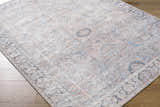 Close up of the Giona Washable Area Rug featuring a traditional Persian pattern in blue, charcoal, and pastel red. Corner