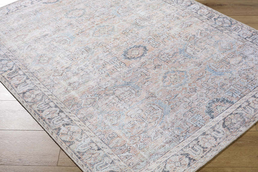 Close up of the Giona Washable Area Rug featuring a traditional Persian pattern in blue, charcoal, and pastel red. Corner