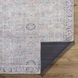 Close-up of the Giona Washable Area Rug showing its vintage Persian design and colors: blue, charcoal, light blue, and pastel red. Fold
