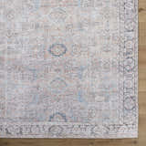 Close-up of the Giona Washable Area Rug. Machine woven with a vintage Persian pattern in blue, charcoal, and pastel red. Corner