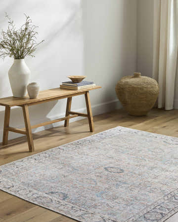 Living room scene with a light blue Giona Washable Area Rug, wood bench, vases, books, and woven basket for a farmhouse feel. Roomscene-Rectangle