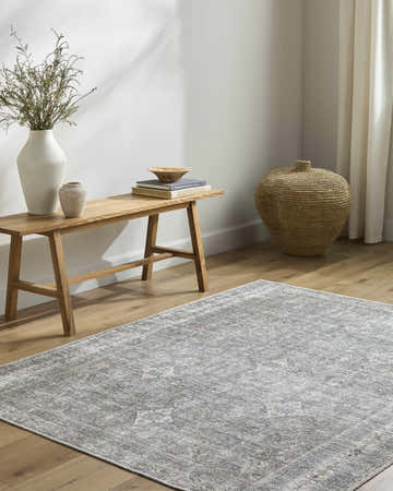 Neutral living room with wood floors and Kelda Washable Area Rug in gray, bench with vases, and woven basket. Roomscene-Rectangle