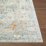 Close-up of Ezri Washable Area Rug showing beige, light blue, and orange traditional farmhouse pattern on wood floor. Front