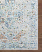 Close-up of the Ezri Washable Area Rug with a traditional light blue, beige, and orange pattern on a wood floor. Swatch