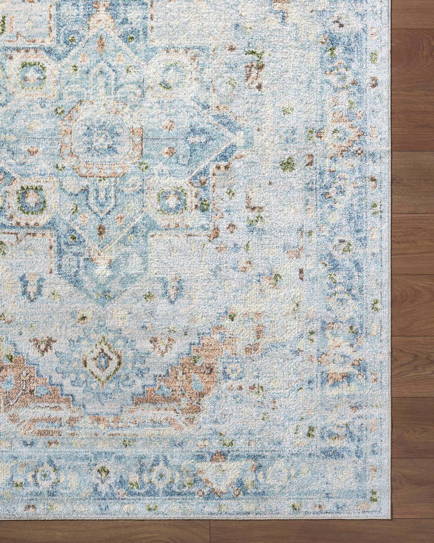 Close-up of the Ezri Washable Area Rug with a traditional light blue, beige, and orange pattern on a wood floor. Swatch
