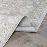Close-up of the Gael Boutique Washable Rug showing its light blue, olive, and tan vintage pattern and machine-woven construction. Fold