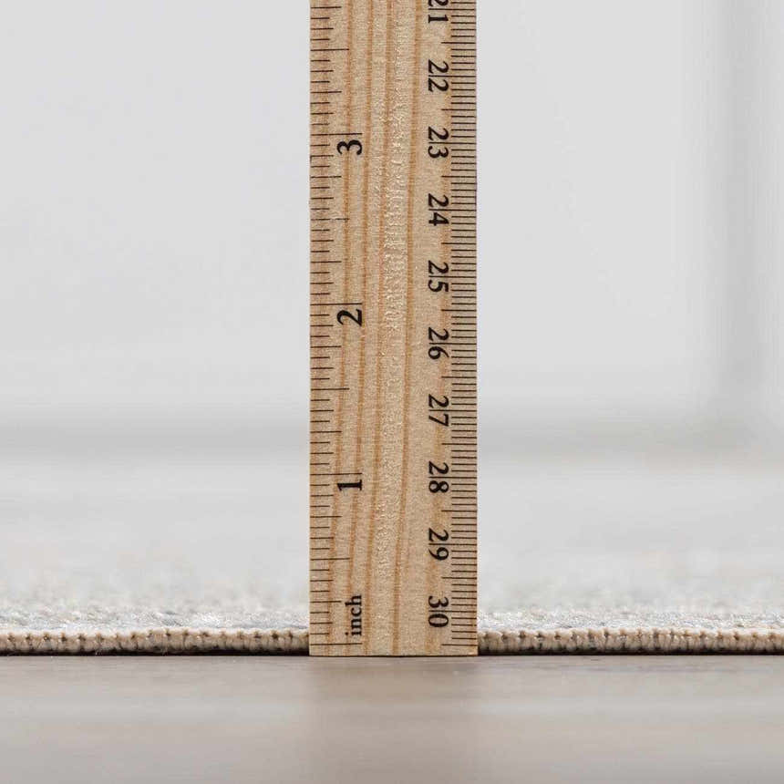 Close up of the Gael Boutique Washable Rug pile height, showing the rug's thickness with an inch ruler. Pile