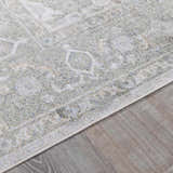 Close-up of Gael Boutique Washable Rug. Light blue, olive, tan, and yellow vintage pattern on a machine-woven polyester rug. Corner