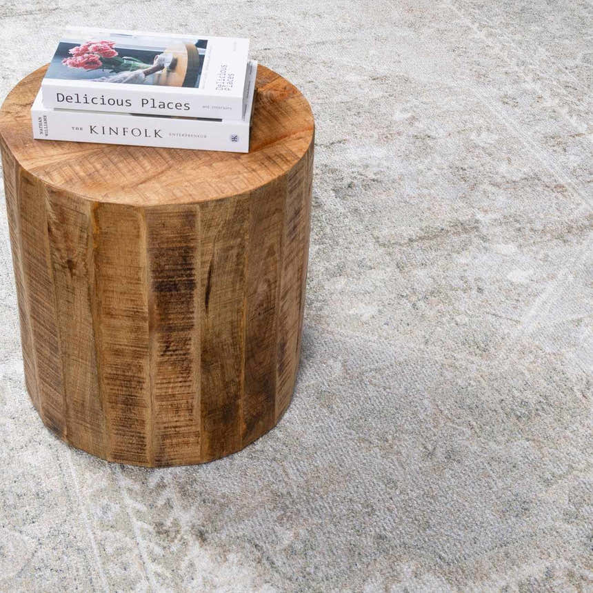 Close-up of the light blue and olive Gael Boutique Washable Rug with a vintage pattern and a wooden side table. Styleshot