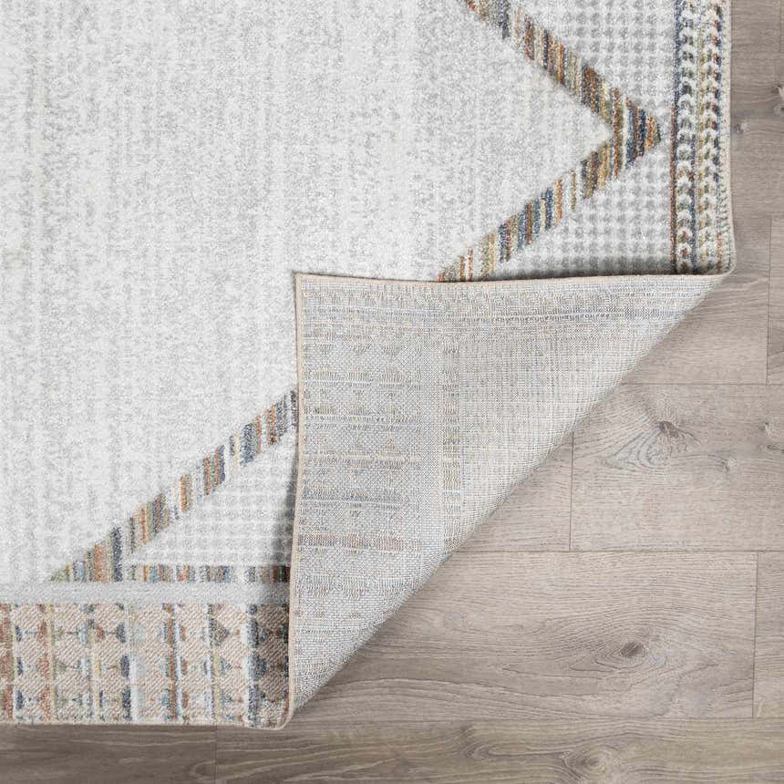 Close-up of Remy Washable Area Rug in bone and gray with geometric pattern and folded corner showing rug backing. Fold