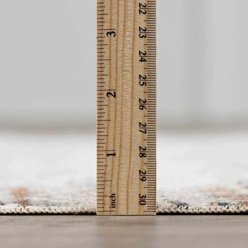 Close-up of the Remy Washable Area Rug showing its pile height with a ruler. Colors: Bone, Driftwood, Gray, Nutmeg, Smoke. Pile