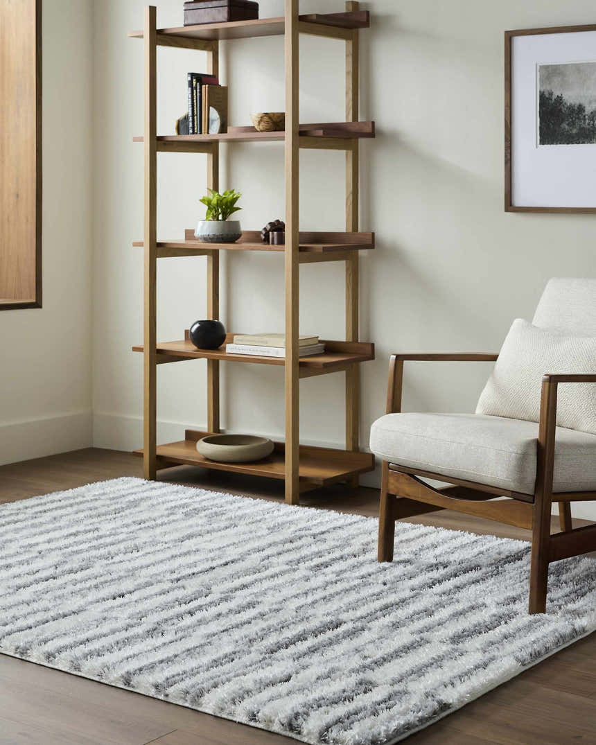 Living room scene with a light slate and cream Anevay Gray Area Rug, wood chair, and bookshelf. Roomscene-Rectangle