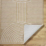 Close-up of the beige Deron Washable Area Rug showing the geometric pattern and non-slip backing. Fold