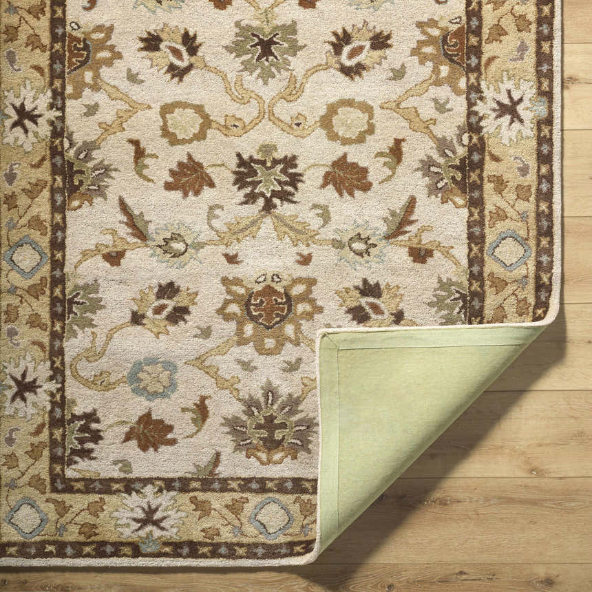 Close-up of the Smoot Area Rug. Beige wool rug with traditional floral pattern in brown, olive, and slate blue tones. Fold