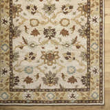 Close-up of the hand-tufted Smoot Area Rug. Beige wool rug with traditional brown, olive, and slate floral pattern. Corner