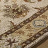 Close-up of the hand-tufted Smoot Area Rug. Beige wool rug with traditional brown, tan, and olive floral and geometric patterns. Texture